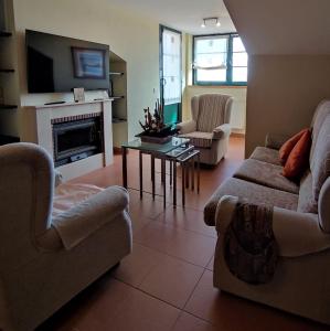 un soggiorno con 2 divani e un camino di Espectacular Dúplex con piscina y cancha de padel a Luanco