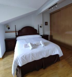una camera da letto con un grande letto con due asciugamani di Espectacular Dúplex con piscina y cancha de padel a Luanco