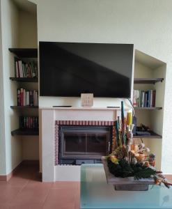 un soggiorno con camino e TV a schermo piatto di Espectacular Dúplex con piscina y cancha de padel a Luanco