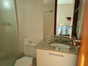a bathroom with a toilet and a sink and a mirror at Apto temporada Cabo Frio in Cabo Frio