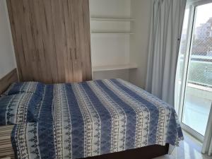 a bedroom with a blue and white bed with a window at Apto temporada Cabo Frio in Cabo Frio