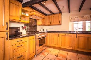 a kitchen with wooden cabinets and a stove top oven at Pear Tree Cottage in Ratton Village