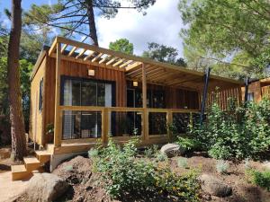a house in the woods with a lot of windows at Camping Arutoli in Porto-Vecchio