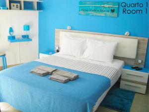 Un dormitorio azul con una cama con toallas. en Tiago & Jorge Guesthouse, en Nazaré