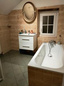 a bathroom with a tub and a sink and a mirror at "Rêves de Gamins" Chambre de gauche, 4 couchages dans gîte de campagne "La Camusière", proche du Pôle Européen et du circuit des 24h in Champagné
