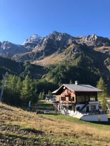 una casa su una collina con montagne sullo sfondo di La Piana Appartamenti ad Alpe Devero
