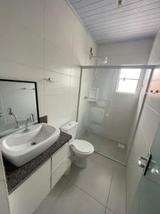 uma casa de banho branca com um lavatório e um WC em Hospedagem Confortável e Prática para viajantes e férias - Próxima à BR-101 em São José