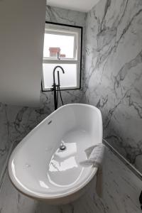 a white bath tub in a bathroom with a window at Ty Belgrave - Apartment 4 in Aberystwyth