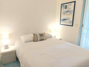 una camera da letto con un letto bianco e un cuscino sopra di Plage la Salis 3 chambres, Jardin - 3 bedrooms a Antibes