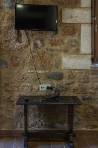 a television on a stone wall with a table with a remote control at Stone House Messinia in Málta