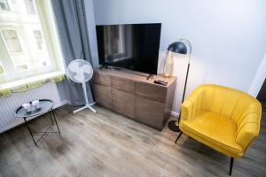 a living room with a yellow chair and a television at Gwiezdny Pył in Toruń