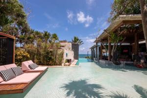 a pool at a resort with lounge chairs and the ocean at Mi Amor Boutique Hotel-Adults Only in Tulum