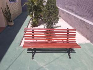 un banc rouge assis sur un trottoir à côté d'un bâtiment dans l'établissement Hostel Parquelândia, à Fortaleza