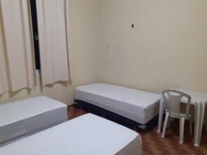 um quarto com duas camas e uma cadeira em Hostel Parquelândia em Fortaleza