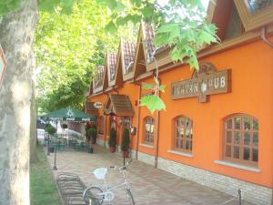 um edifício laranja com uma bicicleta estacionada em frente em Platán Panzió em Nagyszénás