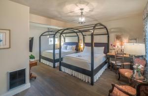 a bedroom with two beds and a desk and a room with a bedsenalsenal at L'Auberge Carmel, Relais & Chateaux in Carmel