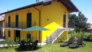 een geel huis met een groep stoelen en een paraplu bij Casetta San Giovanni in Barolo