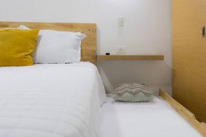 a bedroom with two beds with white sheets and a yellow pillow at Very Special Place Apto in Guatemala