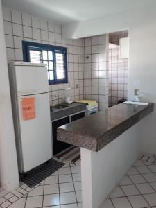 a kitchen with a white refrigerator and a sink at Porto Canoa Apartamento in Aracati