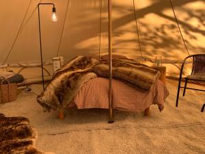 a bed in a tent with a blanket on it at Karula Stay - Exclusive Glamping Experience with Private Sauna in Ähijärve