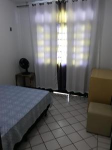 a bedroom with a bed and a chair and a window at Porto Canoa Apartamento in Aracati