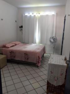 a bedroom with a bed and a table and a fan at Porto Canoa Apartamento in Aracati