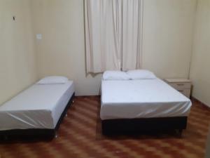 two beds in a small room with a window at Hostel Parquelândia in Fortaleza