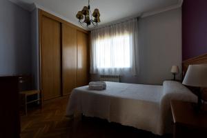 sypialnia z białym łóżkiem i oknem w obiekcie Playa de Llas w mieście Foz