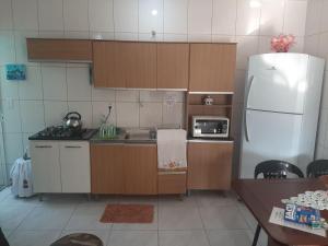 a kitchen with wooden cabinets and a white refrigerator at Casa do Jaime in Itapoa