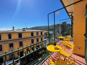 einen Balkon mit gelben Tischen und Stühlen auf einem Gebäude in der Unterkunft Casa Irene terrazza vista mare e garage in Porto Venere
