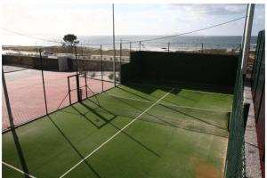 a tennis court with a view of the ocean at Espectacular chalet complejo turístico Raeiros - O Grove in O Grove