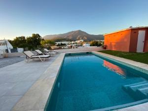 a swimming pool with two chairs and a house at Casa Delfina in Estepona