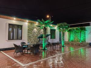 un patio con sillas y palmeras bajo la lluvia en Nice Apartments Tbilisi, en Tiflis