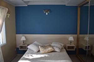 Un dormitorio con una pared azul y una cama con almohadas en dolce casa en San Clemente del Tuyú