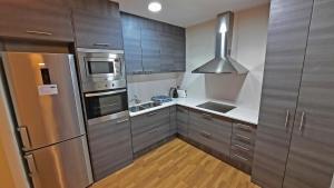 una cocina con electrodomésticos de acero inoxidable y armarios de madera en L'Astrolabi, en Ripoll