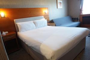a bedroom with a large white bed and a blue chair at The Park Hotel in Liverpool