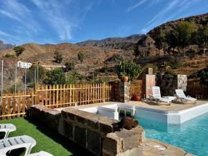 a backyard with a pool with chairs and a fence at casa rural LA LIMERA con piscina privada in Santa Lucía