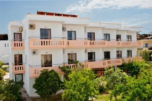 an apartment building with pink balconies and trees at Thodorou Villa in Agia Marina Nea Kydonias