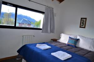 a bedroom with a blue bed with a large window at Posada San Antonio in El Chalten