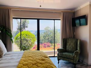 um quarto com uma cama e uma cadeira e uma grande janela em Langalanga on the mountain bend em Tzaneen