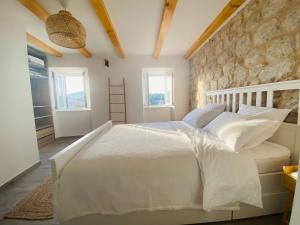 a bedroom with a white bed with a stone wall at Villa Piscitelli in Cavtat
