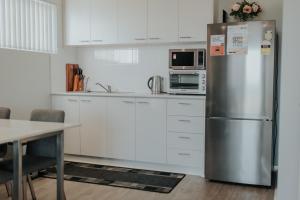a kitchen with white cabinets and a stainless steel refrigerator at Beach House at SeaScapes.. in Mandurah