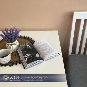 un livre sur une table avec une tasse de café et un vase de fleurs dans l'établissement ZOE apartment, à Vršac