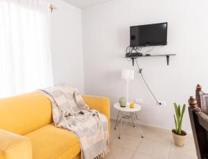 een woonkamer met een gele bank en een tv bij casa quinta, alquiler temporario in Toay
