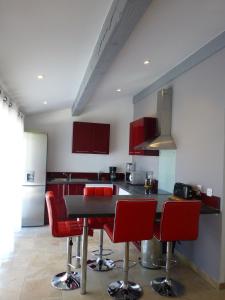 a kitchen with red chairs and a black counter top at Le Gîte du Moulin in Sarrians