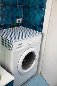 a washing machine in a bathroom with a blue tiled wall at Casa Abba-2 in Alessandria