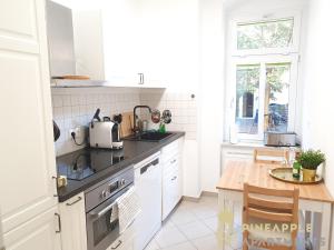 een witte keuken met een wastafel en een tafel bij Ruhiges Hinterhof Apartment im Herzen der Neustadt in Dresden