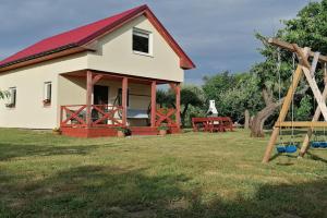 uma casa branca com um telhado vermelho e um parque infantil em holiday home, Kolczewo em Kolczewo