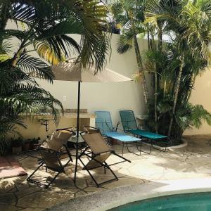 - un groupe de chaises et un parasol à côté de la piscine dans l'établissement Bed and Breakfast Pecarí, à Cancún