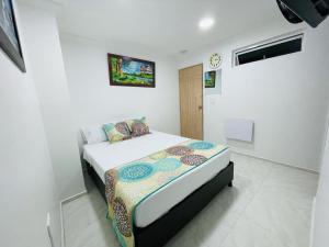 1 dormitorio con 1 cama y reloj en la pared en Hotel Eterna Primavera en Medellín